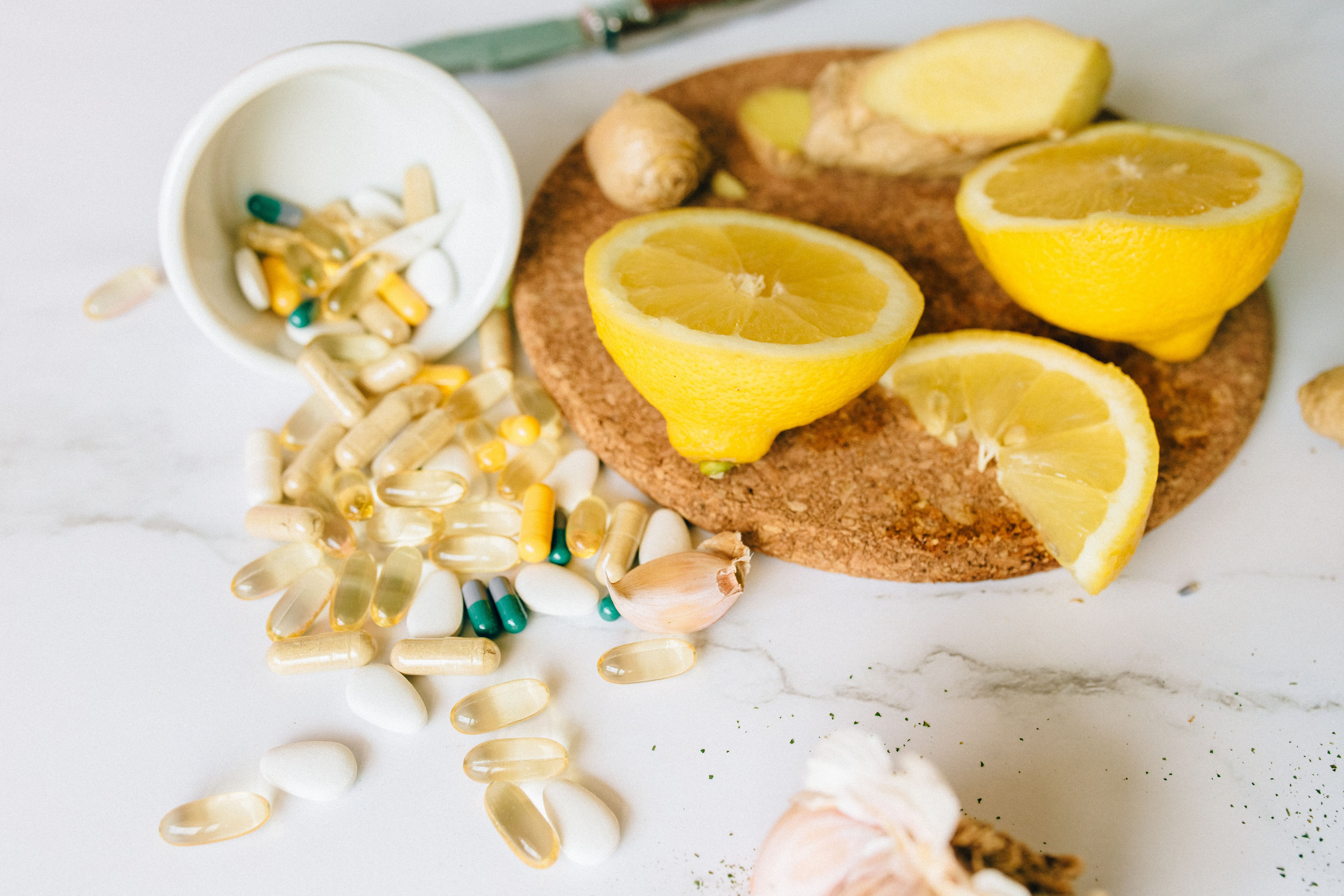 Tongkat Ali roots, lemon halves, and capsules on a cork surface